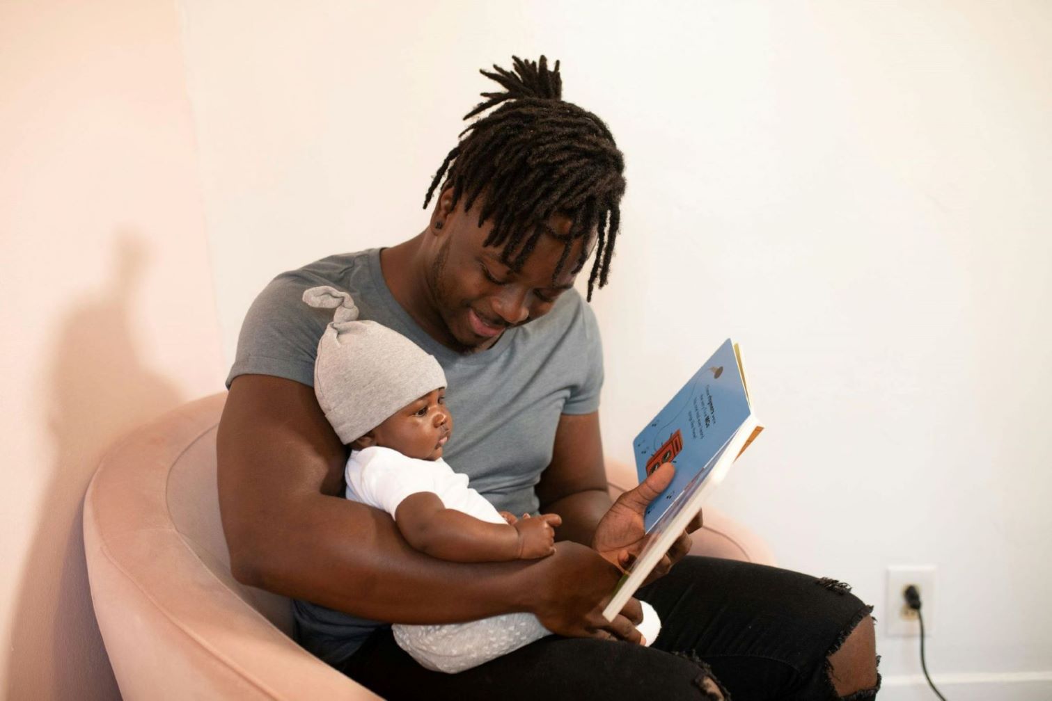 a black man holding his baby child reading book