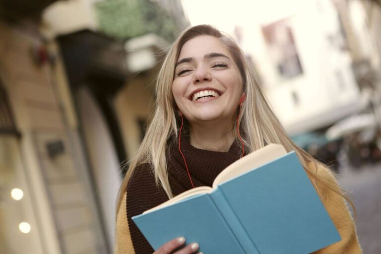 a woman reading book in the street walking smiling